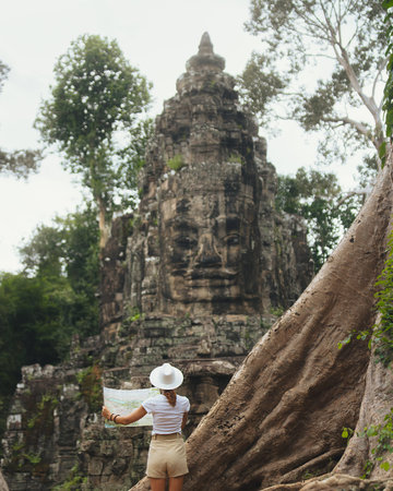 Female Traveler Reading Map At Ancient Angkor Temple Ruins In Cambodiaの写真素材