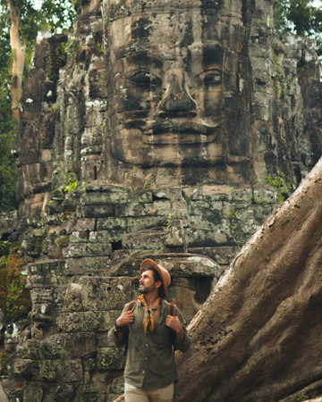 Male Traveler At Bayon Face Tower In Ancient Angkor Jungle Templeの写真素材