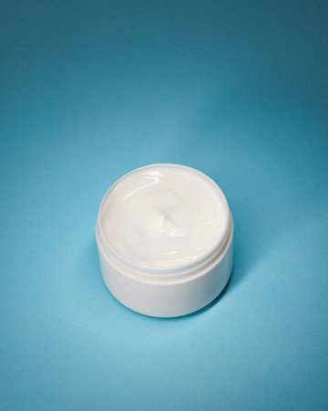 Open Face Cream Jar On Blue Background With Copy Space, Studio Flat Lay