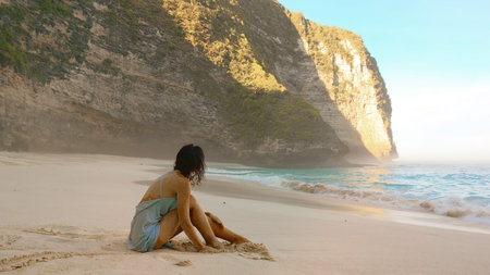Woman Relaxing On Kelingking Beach Bali By Golden Cliffs And Sea Today