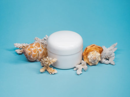 White Cosmetic Cream Jar With Seashells On Blue Background Flat Layの写真素材