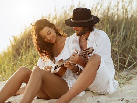 Boho Couple Playing Ukulele Together on Sandy Beach at Sunset in Summer Light