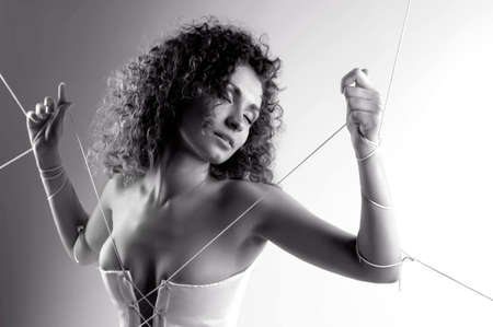 girl in white dress with her hands tied with ropeの写真素材