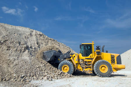Industrial tractor rides along the embankment of industrial waste