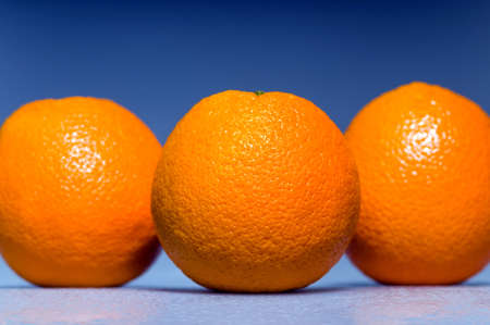 three oranges lying on the ground, covered with drops of waterの写真素材