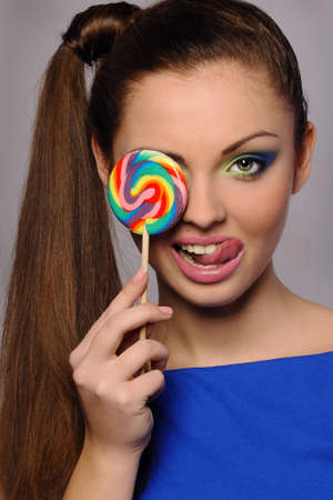 Beautiful young girl sucks sweet on stickの写真素材