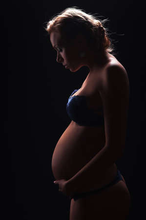 A pregnant woman in lingerie on black backgroundの写真素材