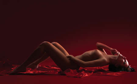 beautiful nude young woman on a red backgroundの写真素材