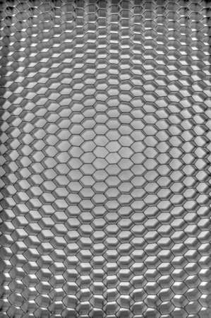 Silver metal background with hexagon holes and light reflectionの写真素材