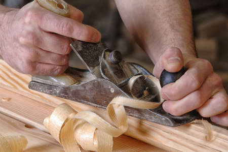 Man hands with carpenters plane on wooden background