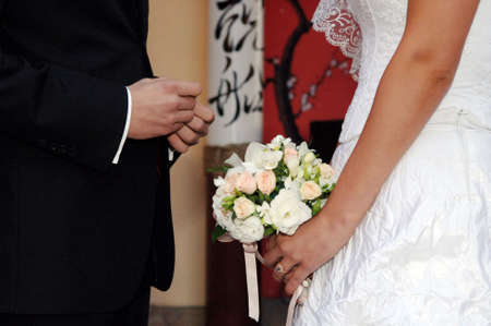 Bride putting a ring on groom's finger during wedding ceremonyの写真素材