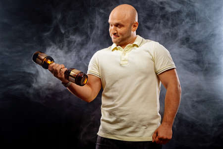 happy man with lots of beer shakes his biceps on a black background