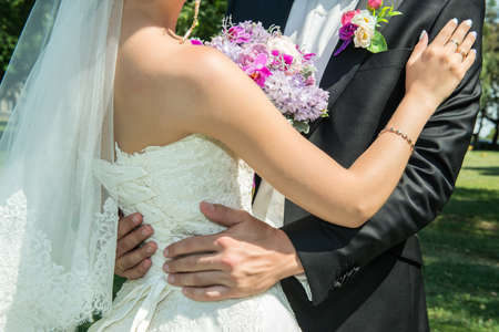 Wedding couple holding hands and hugging body part