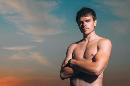 Handsome good-looking man on beach smiling happy after swimming during vacation in holiday resort. Male model enjoying sunny holidays under the sun. Young Caucasian man in his twenties.の写真素材