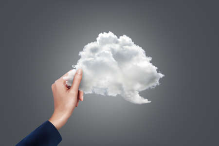 Close up business woman holding cloud shape at grey background. Cloud computing concept.の写真素材