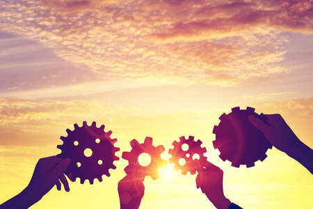 Silhouette hands holding gear from at sunlight background.の写真素材