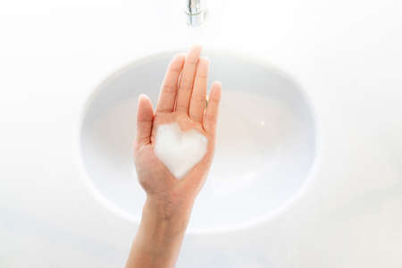 White bubbles foam soap Heart shaped in hands women