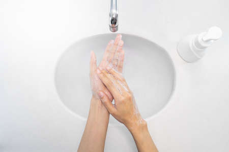 Close up of woman washing her hands for protection, and soap pressed bottle sinks top view.の写真素材