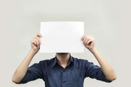 Close up hands man holding behind a paper blank for banner on gray backgroundの写真素材