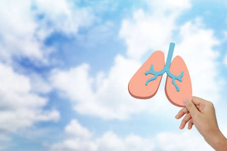 Hand holding human lung icon at background.