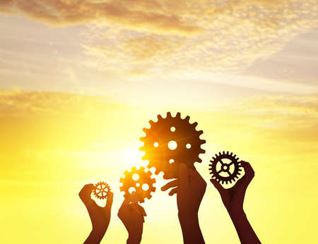 Silhouette hands holding gear from at sunlight background.の写真素材