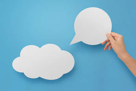 Hand holding an empty speech bubble and hold the cloud empty at blue background.の写真素材