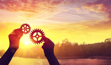 Silhouette hands holding gear from at sunlight background.の写真素材