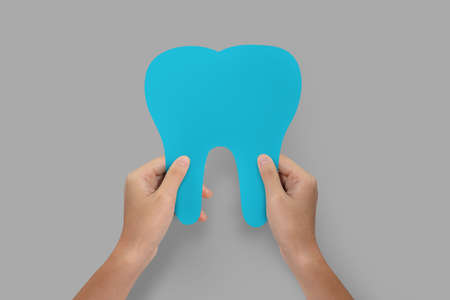 Hands holding blue tooth isolated.  Teeth care and protection concept.の写真素材