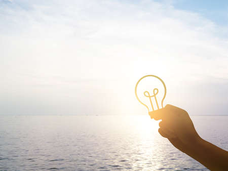 Silhouette hand holding lamp sign for idea concept.