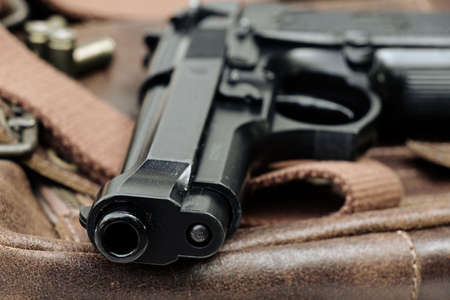 Semi-automatic handgun lying over a Leather handbag, 9mm pistol, Close-up Barrel