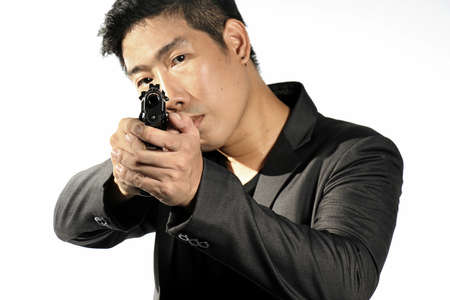 Asian Businessman aiming with handgun, Man in a suit preparing to shoot. Isolated on white. Semi-automatic handgun, 45 pistol.の写真素材