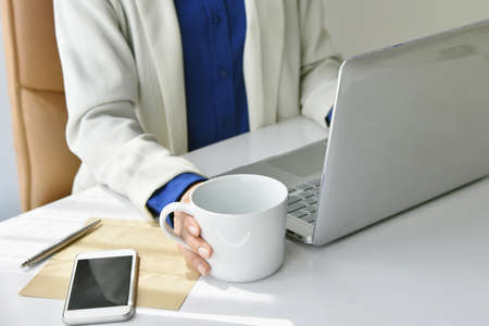 Coffee for refreshment, Business woman working on laptop and drinking coffee.の写真素材