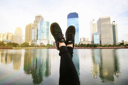 Feet point to the blue sky with modern city background, Relaxing concept.の写真素材