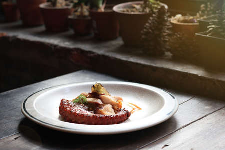 Grilled octopus tentacles with lemon and parsley leaves on dish.の写真素材