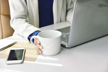 Coffee for refreshment, Business woman working on laptop and drinking coffee.の写真素材