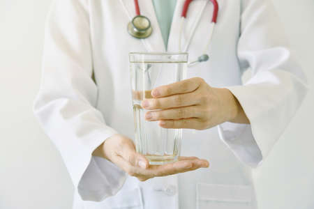 Doctor holding a glass of clear fresh water, Doctor recommend drinking healthy water.の写真素材