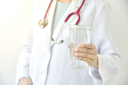 Doctor holding a glass of clear fresh water, Doctor recommend drinking healthy water.の写真素材
