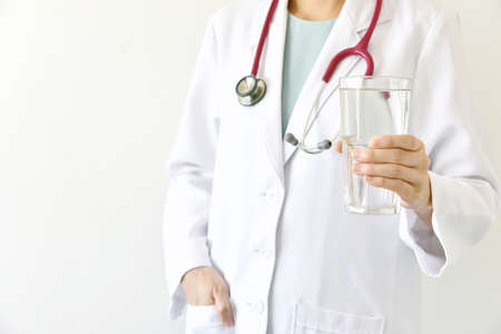 Doctor holding a glass of clear fresh water, Doctor recommend drinking healthy water.の写真素材
