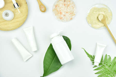 Cosmetic bottle containers with green herbal leaves, Blank label package for branding mock-up, Natural organic beauty product concept.の写真素材