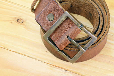 Leather belt with a buckle on a wooden board. Men fashion and accessories.の写真素材