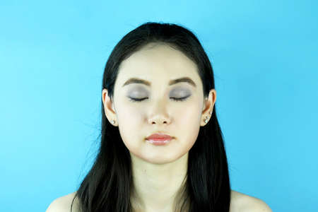 Fashion portrait of beautiful sensual girl with bright makeup. Beautiful woman applying powder at party. Asian woman getting ready putting makeup on face.の写真素材