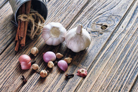 Variety of herb and spices on wooden background. Shallot, Cardamom, Cinnamon sticks, Fresh garlic. Healthy Cuisine ingredients. (Color Process)の写真素材