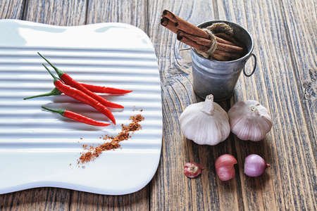 Variety of herb and spices on wooden background. Shallot, Cardamom, Cinnamon sticks, Fresh garlic, Red Chilli pepper. Healthy Cuisine ingredients.の写真素材