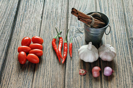 Variety of herb and spices on wooden background. Shallot, Cardamom, Cinnamon sticks, Fresh garlic, Red Chilli pepper. Healthy Cuisine ingredients.の写真素材