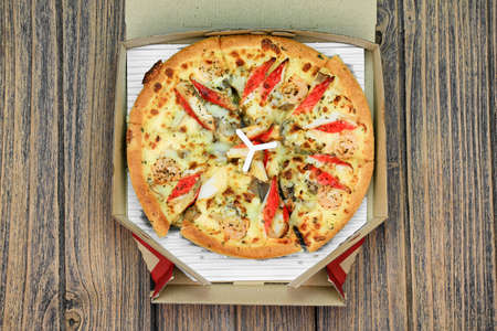 Pizza in the delivery box on wooden background, Fast food.の写真素材