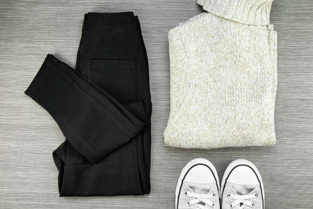 Collection of warm autumn clothes on a light wooden background. Knitted sweaters, leggings and sneaker. Set of winter fashion clothes. (Color Process)の写真素材