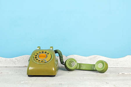 Still life with old green telephone on wooden table, Rotary telephone on wood table.
