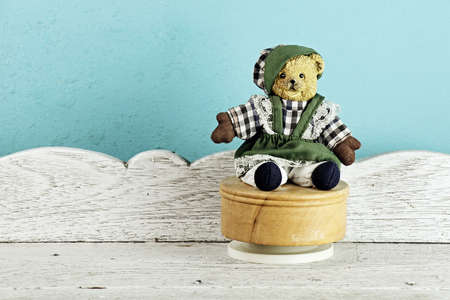 Vintage Teddy Bear toy alone on white wooden table in front of blue background. (Vintage Style...