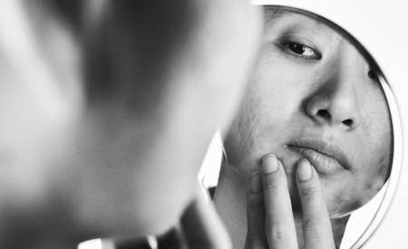 Skin problems and acne scar, Woman looking at mirror worried about her facial problem, Mirror reflection, Beauty concept.の写真素材