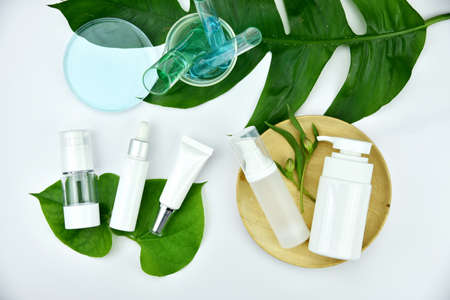 Cosmetic bottle containers with green herbal leaves, Blank label for branding mock-up, Natural beauty product concept.の写真素材